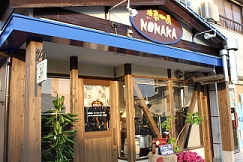 焙煎珈房NONAKAの店頭写真。焙煎珈房NONAKAと書かれたかわいい看板が掲げられ、店の前には小さな焙煎機が飾られている。